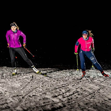 Two women in the dark on the night slope in Tri